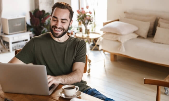happy man working on laptop in studio apartment